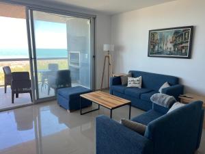 ein Wohnzimmer mit blauen Sofas und einem Tisch in der Unterkunft Amplio con vista al mar in Balneario Monte Hermosa