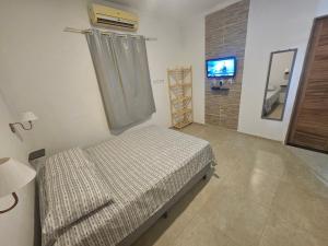 ein Krankenhauszimmer mit einem Bett und einem TV in der Unterkunft Sol & Vento Chalés - Chalé Cardeiro in São Miguel do Gostoso