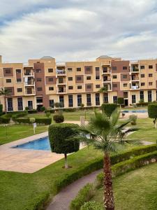 a large apartment complex with a palm tree and a building at Appartement en résidence privée in Marrakech +25 photos