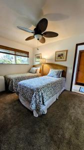 een slaapkamer met twee bedden en een plafondventilator bij Seaside Retreat Condo in Kailua-Kona