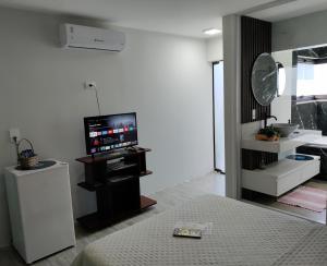 a white room with a bed and a television at Suíte Máster Luxo - Lar-Doce-Mar in Barra Velha