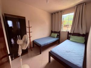安格拉杜斯雷斯Adialas Tour Angra dos Reis!的客房设有两张床、风扇和窗户。