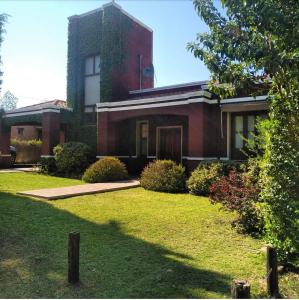 ein rotes Backsteinhaus mit einem Rasenplatz in der Unterkunft La Morada in Mina Clavero