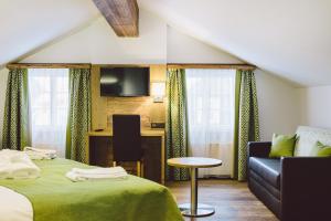 a hotel room with a bed and a couch and a desk at Hotel & Restaurant Zum Schwarzen Bären in Andermatt