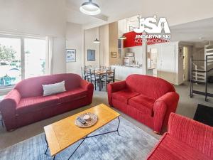 a living room with two red chairs and a table at Razorback 2 in Jindabyne