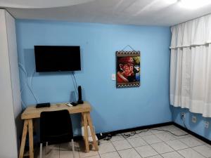 una camera con una parete blu, un tavolo e una TV di Atlântico Flat - Pé na Areia em Ponta Negra -114 a Natal
