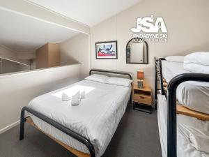 a small bedroom with two beds and a mirror at Razorback 2 in Jindabyne