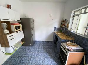 a small kitchen with a refrigerator and a stove at Hostel 5C - Itanhaém in Itanhaém