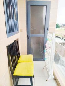a yellow bench sitting on a balcony with a door at Résidence Ahydeney in Abidjan