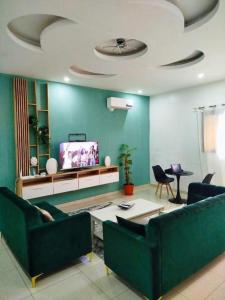 a living room with two green couches and a tv at Résidence Ahydeney in Abidjan