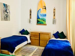 two beds in a room with a surfboard on the wall at Cozy 1BR Bungalow with Kitchen in Eco Garden Nature Escape in Agadir