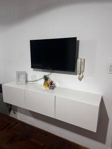 a white entertainment center with a flat screen tv on a wall at Carlis Home in Cordoba