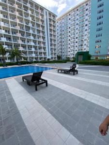 two benches next to a swimming pool in a building at Aesthetic Vibes Condo 2br Near Airport in Manila +3 photos