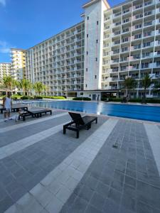 a swimming pool with benches in front of a large building at Aesthetic Vibes Condo 2br Near Airport in Manila