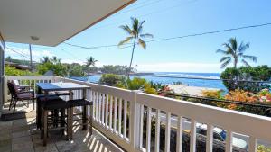 een balkon met een tafel en stoelen en uitzicht op de oceaan bij Seaside Retreat Condo in Kailua-Kona