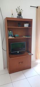 a wooden entertainment center with a television in it at Oásis Flórida in Peruíbe