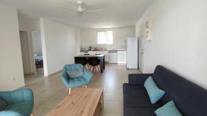 a living room with a couch and a table and a kitchen at L'Îlot de la Marina in Le Marin