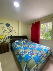 a bedroom with a bed with a comforter and a window at hostal los cascabeles de la sierra in Santa Marta +47 photos