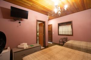 une chambre avec deux lits et une télévision à écran plat dans l'établissement Ecopousada Serra Verde, à Glaura