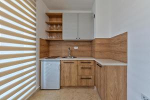 a kitchen with wooden cabinets and a white dishwasher at Cozy apartment in Čajetina