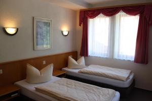 two beds in a room with red curtains at Pension Ujut in Bad Langensalza