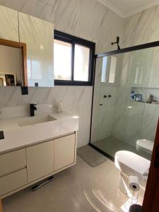 ein weißes Badezimmer mit Waschbecken und Dusche in der Unterkunft Casa Completa Condomínio Rosa Internacional - ao lado Sufland - Garopaba-SC in Garopaba