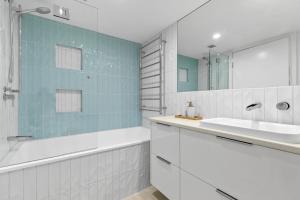 a bathroom with a sink and a tub and a mirror at 6 Parkshores Sunshine Location Location Location 100m to beach access in Sunshine Beach +16 photos