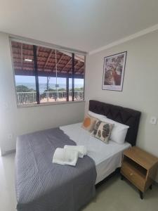 a bedroom with a bed with a table and a window at Jabuticaba Sabará - Frente ao Mar na Praia de Meaípe, Guarapari in Guarapari
