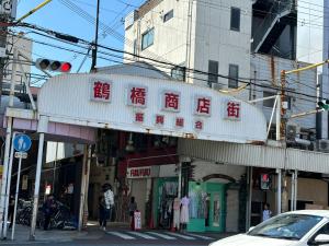 una señal para una tienda en una calle de la ciudad en Tamatsukan 玉津館, Detached Hse, JR Tsuruhashi 7min, Kansai Airport 關西空港 57 mins, Namba 6 mins, Nihonbashi 4 mins, Universal Studio 37 mins, Nara 30 mins, Early Check In, en Osaka