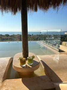 two cups sitting on a table in front of a pool at Villa Macarena Apartamentos Boutique - Only Adults in Puerto Escondido