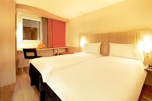 a hotel room with a large white bed and a desk at ibis Paris Montmartre Sacré-Coeur in Paris +27 photos