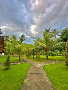 einen Pfad in einem Park mit Palmen und Gras in der Unterkunft The Dulu Penida in Nusa Penida