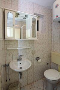 ein Badezimmer mit Waschbecken, Toilette und Spiegel in der Unterkunft Apartments Marina in Sukošan