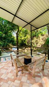 two wooden benches under an umbrella on a patio at hostal los cascabeles de la sierra in Santa Marta