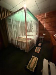 a bedroom with a canopy bed with curtains and rugs at Woodland Hideaway in Sinharaja in Deniyaya
