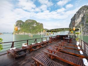 Una cubierta de un barco con mesas y sillas de madera. en Garden Bay Classic cruise, en Ha Long