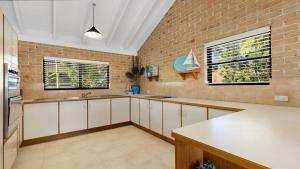 a kitchen with white cabinets and a brick wall at Seahorse On Fawcett in Brunswick Heads