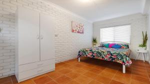 a bedroom with a bed and a white brick wall at Seahorse On Fawcett in Brunswick Heads