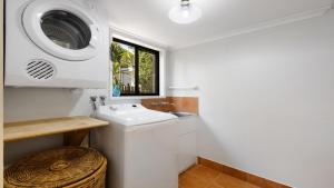 a bathroom with a sink and a washing machine at Seahorse On Fawcett in Brunswick Heads +5 photos