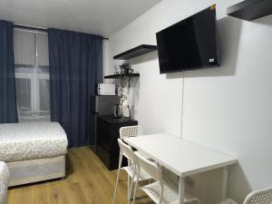 a room with a bed and a desk with a tv on the wall at 4 person room 3min from South Wimbeldon tube station Room2 in London