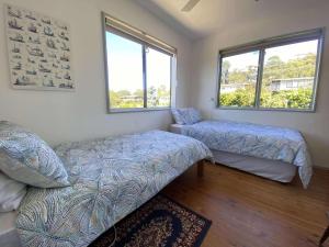 a bedroom with two beds and two windows at 14 Brady Street in Mallacoota