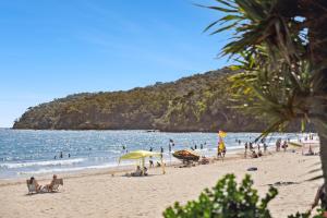 Eine Gruppe von Menschen an einem Strand in der Nähe des Wassers in der Unterkunft Fairshore in Noosa Heads