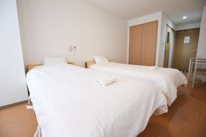 大阪市にあるConnect Innの白いシーツが敷かれた部屋にベッドが2つ