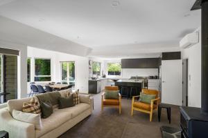Una sala de estar con un sofá y sillas y una cocina. en Emerald Oasis by Sotheby's Luxury Rental Homes, en Wanaka