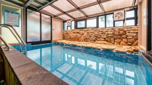 una piscina en un edificio con una pared de piedra en Gyeongju SoraedangA Pension, en Gyeongju