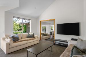 Una sala de estar con un sofá y un televisor de pantalla plana. en Emerald Oasis by Sotheby's Luxury Rental Homes, en Wanaka