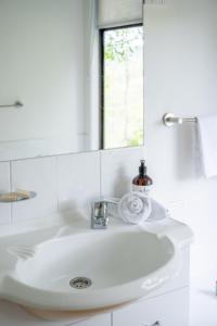 a white sink in a bathroom with a mirror at Personal Sauna & Ice-bath at Kookaburra Cabin in Mudgeeraba