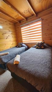 ein Zimmer mit zwei Betten in einer Blockhütte in der Unterkunft Cabaña kiro in Dalcahue