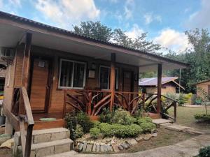 a small house with a porch and some bushes at Mariah Guest House in Port Barton