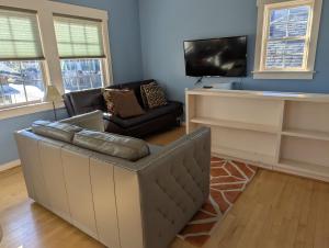 a living room with a leather couch and a tv at Back Alley Apartment, Walk Downtown And Duke in Durham